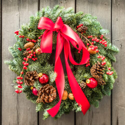 Wreath decorated with red berries, red ribbon, and pine cones