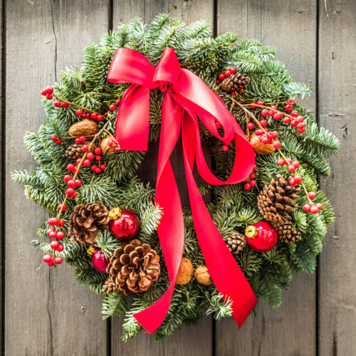 Wreath decorated with red berries, red ribbon, and pine cones